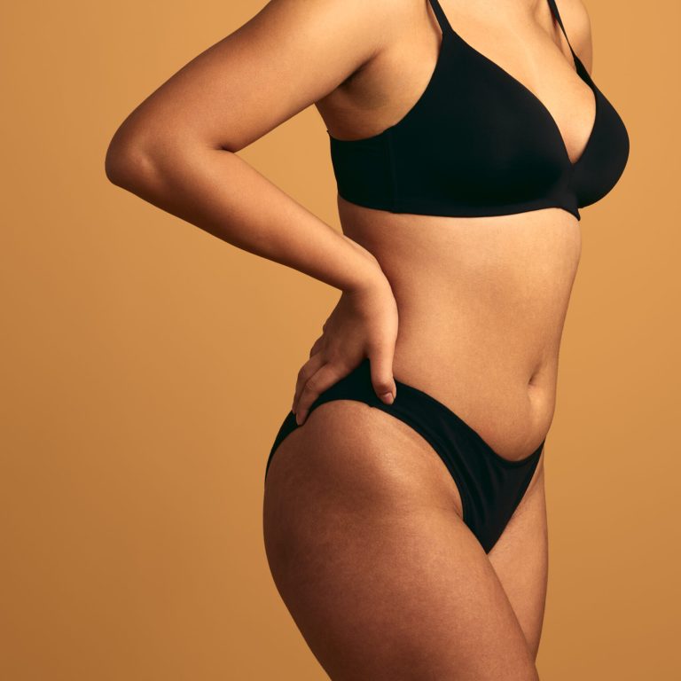 Faceless female model wearing black underwear showing imperfect body as self acceptance on brown background